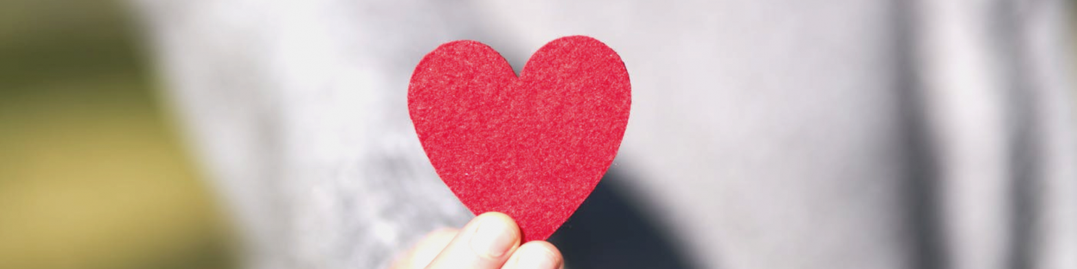 hand holding paper cutout of a red heart